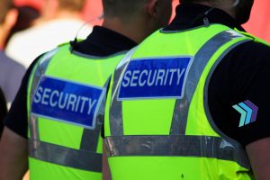 Image of two male security Guards with bright tops on.
